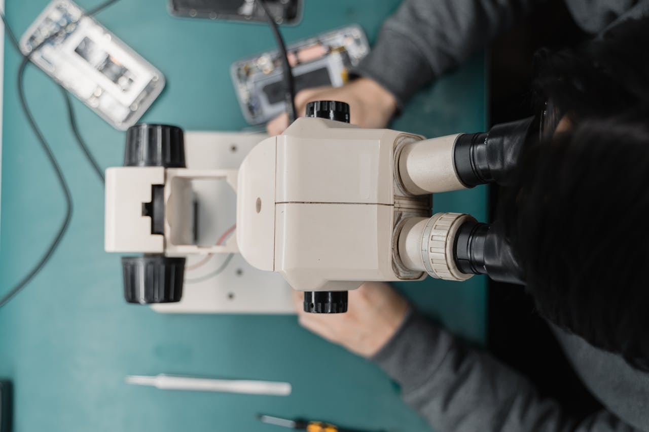 Close-up of a technician using a microscope for phone repair, highlighting precision work.